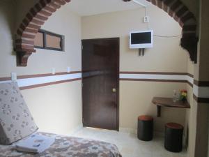 a room with a bed and a door with a tv at Posada Arny in Tepotzotlán