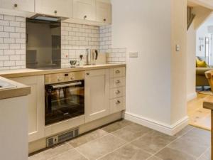 cocina con armarios blancos y horno en The Cottage on Fairbank - Kirkby Lonsdale en Kirkby Lonsdale