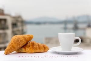 Dois croissants e uma chávena de café numa mesa. em Hotel Philippos em Volos