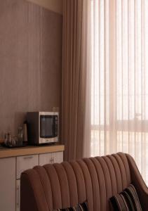 un canapé en face d'une fenêtre avec un four micro-ondes dans l'établissement قوت المصيف للشقق الفندقية, à Hotat bani tamim