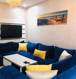 ein Wohnzimmer mit einem blauen Sofa und einem TV in der Unterkunft L impérial appart haut founty in Agadir