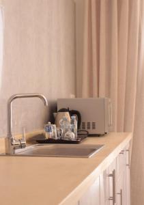 - un comptoir de cuisine avec évier et four micro-ondes dans l'établissement قوت المصيف للشقق الفندقية, à Hotat bani tamim