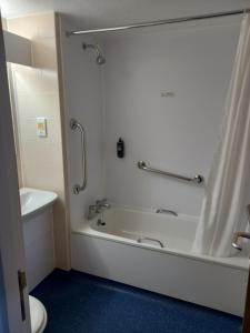 La salle de bains est pourvue d'une baignoire, d'une douche et de toilettes. dans l'établissement Thurrock Hotel M25 Services, à Aveley