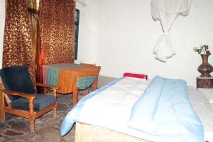 a bedroom with a bed and a chair and a table at La paillotte gorilla place kinigi in Kinigi +10 photos