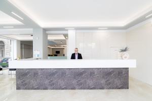 a man standing behind a counter in a lobby at Hotel Philippos in Volos