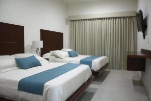 a hotel room with two beds and a television at MARENA Suites & Apartments in Mazatlán