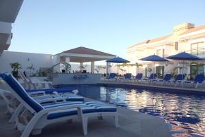 Una piscina con sillas y sombrillas al lado de un edificio. en MARENA Suites & Apartments, en Mazatlán