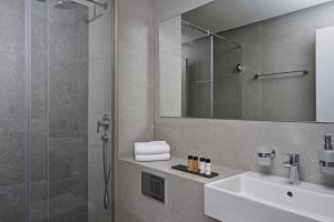 uma casa de banho com um lavatório e um chuveiro com um espelho. em Hestia - Asklipiou 61 em Atenas