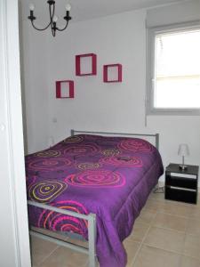 ein violettes Bett in einem Schlafzimmer mit einem Fenster in der Unterkunft résidence le hameau du moulin -- chemin de Gouny 24290 montignac- DORDOGNE in Montignac