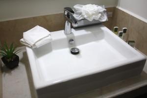 un lavabo blanco en un baño con una bolsa. en MARENA Suites & Apartments, en Mazatlán 15 fotos más