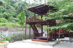 a wooden building with a balcony in a garden at THE DENAI Langkawi in Kuah