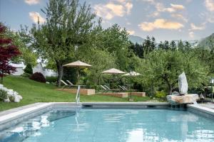 ein großer Pool in einem Garten mit Bäumen in der Unterkunft Hotel AlpenSchlössl in Söll