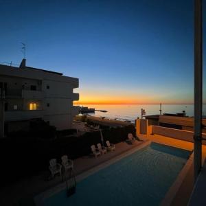 a swimming pool with a view of the ocean at sunset at Palese Profumo di Mare in Santo Spirito