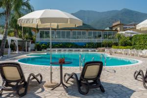 a table with chairs and an umbrella next to a pool at Corte San Lorenzo in Sant'Egidio del Monte Albino