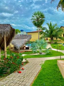 a resort with a pathway and palm trees and grass at Pousada e Chalés Recantos do Mar in Barra Grande
