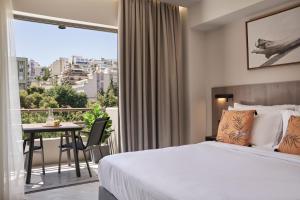 a bedroom with a bed and a balcony with a table at Hestia - Asklipiou 61 in Athens