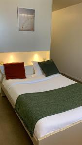 Elle comprend un grand lit avec des oreillers rouges et verts. dans l'établissement Study Hôtel Bordeaux Lormont, à Lormont