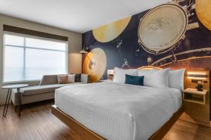 Cambria Hotel Austin Airport في أوستن: غرفة نوم بسرير كبير وأريكة