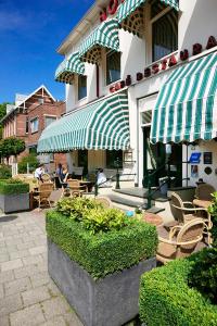 un patio avec des chaises et des parasols en face d'un bâtiment dans l'établissement Hotel Faber, à Hoogezand