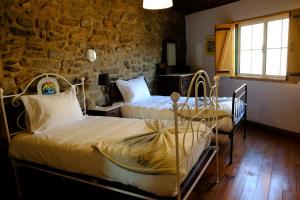 2 letti in una camera con parete in pietra di Vita Portucale ! Countryside Cottage Gem Moncorvo a Torre de Moncorvo