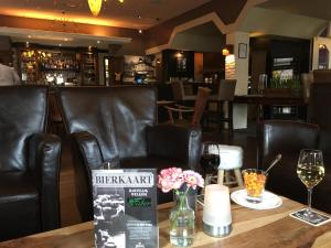 - un bar avec des fauteuils en cuir noir et une table avec des verres à vin dans l'établissement Hotel Faber, à Hoogezand