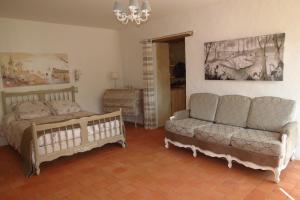 ein Schlafzimmer mit einem Bett, einem Sofa und einem Kronleuchter in der Unterkunft Gîte écoconçu charmant proche zoo de la Flèche in Clermont-Créans