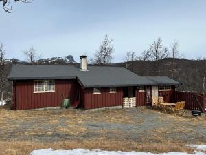 une grange rouge avec une table et des chaises devant elle dans l'établissement Hjemmekoselig hytte med fantastisk utsikt, à Beitostøl