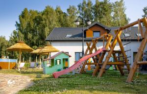 a childrens playground with a slide and a play house at Osada Słuszewo - Apartamenty Restauracja Wydarzenia in Gniewino