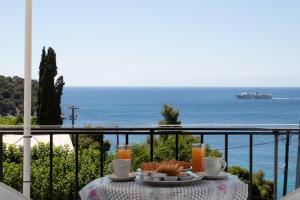 a table with bread and drinks on a balcony with the ocean at Stafylos Rooms in Stafylos