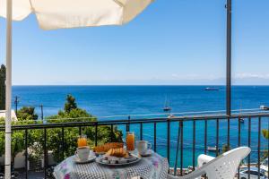 a table with food on a balcony with a view of the ocean at Stafylos Rooms in Stafylos