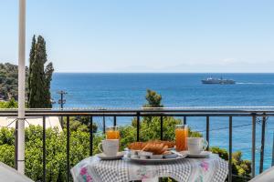 a table with food and drinks on a balcony with the ocean at Stafylos Rooms in Stafylos