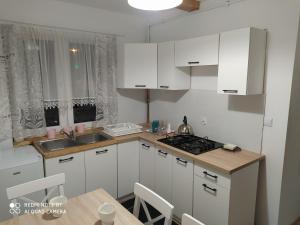 a kitchen with white cabinets and a sink and a table at Domek przy parku in Susiec