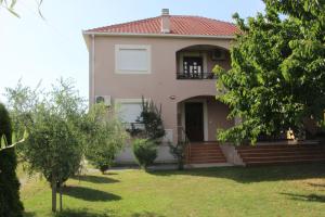 a house with a balcony and a yard with trees at Apartman na rijeci Cijevni in Podgorica
