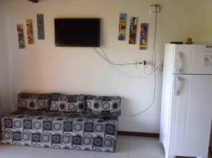 Habitación con sofá y TV en la pared. en Flat Casagrande, en Morro de São Paulo