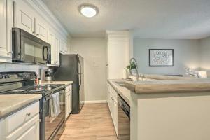 a kitchen with white cabinets and a black refrigerator at Auburn Condo with 2 Pools Less Than 2 Mi to University! in Auburn