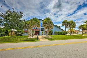 a blue house with palm trees in front of a street at Lovely Palm Coast Retreat with Outdoor Kitchen in Palm Coast