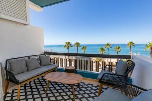 a balcony with a couch and chairs and the beach at Quarteira Beach Stunning Apartment in Quarteira