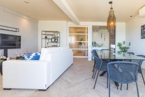 a living room with a white couch and a table and chairs at Quarteira Beach Stunning Apartment in Quarteira