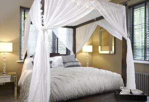 1 dormitorio con cama con dosel y cortinas blancas en Windfalls Boutique Hotel en Crawley