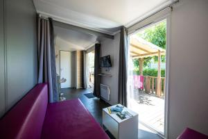 a living room with a purple couch and a sliding glass door at Charmant camping Familiale 3 Etoiles vue 360 plage piscine à débordement empl XXL in Labeaume