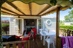 a couple sitting on the porch of a house at Charmant camping Familiale 3 Etoiles vue 360 plage piscine à débordement empl XXL in Labeaume