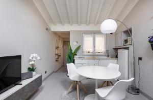 a white kitchen with a white table and chairs at HOUSE Cavour 24 In the heart of Downtown Parma in Parma