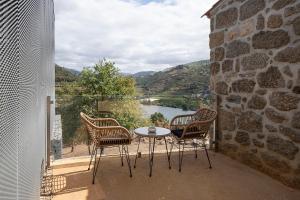 einen Tisch und Stühle auf einem Balkon mit Flussblick in der Unterkunft Quinta de São Pedro in Barrô