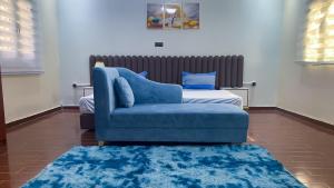 Hotel Suites TALHAYA, NOUAKCHOTT في نواكشوط: غرفة معيشة بها كرسي ازرق وسرير