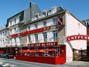 a hotel with red tables and umbrellas in front of it at The Originals Boutique, Hôtel d'Angleterre, Fécamp in Fécamp