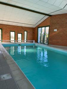 a large blue swimming pool in a brick building at Hôtel Le Gois in Beauvoir-sur-Mer