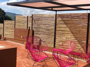 a group of pink chairs and an umbrella on a patio at Casa Crónica in Oaxaca City