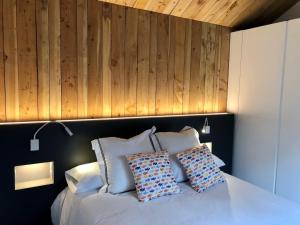 1 dormitorio con cama blanca y pared de madera en Cabañas Rias Baixas, en Pobra do Caramiñal