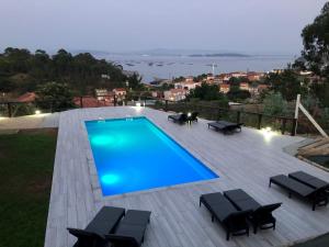 a swimming pool on a wooden deck with black chairs at Cabañas Rias Baixas in A Pobra do Caramiñal
