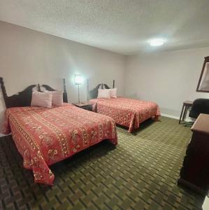 a hotel room with two beds with red sheets at Bradbury Inn in Big Spring